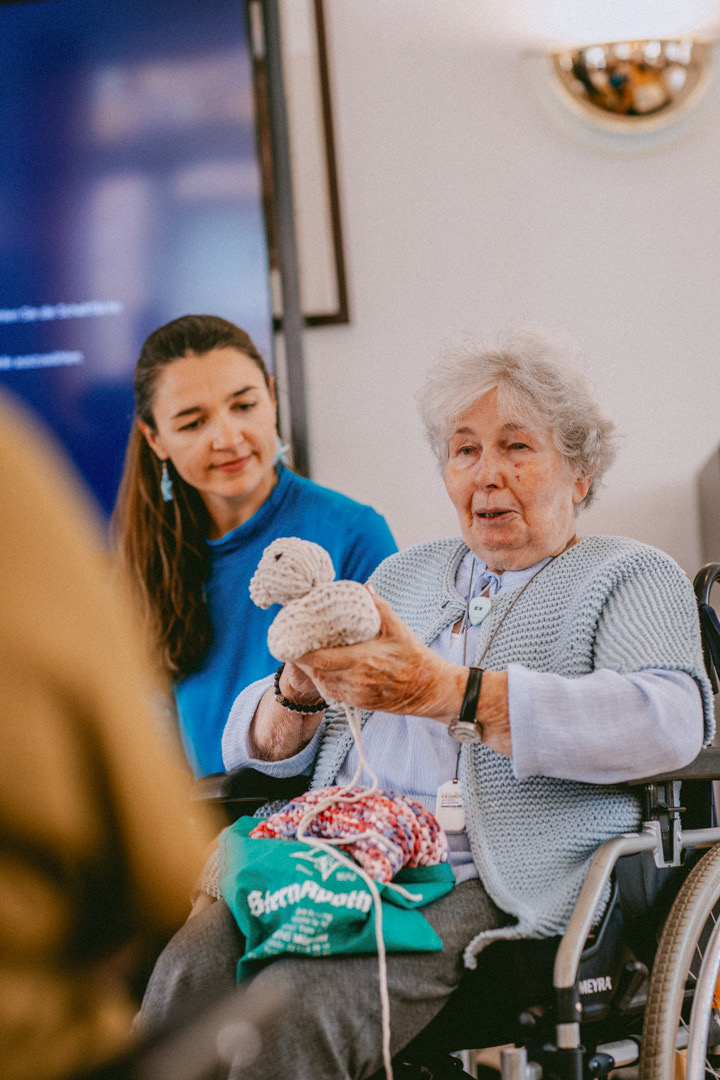 Margret showing a knitted piece from her wheelchair