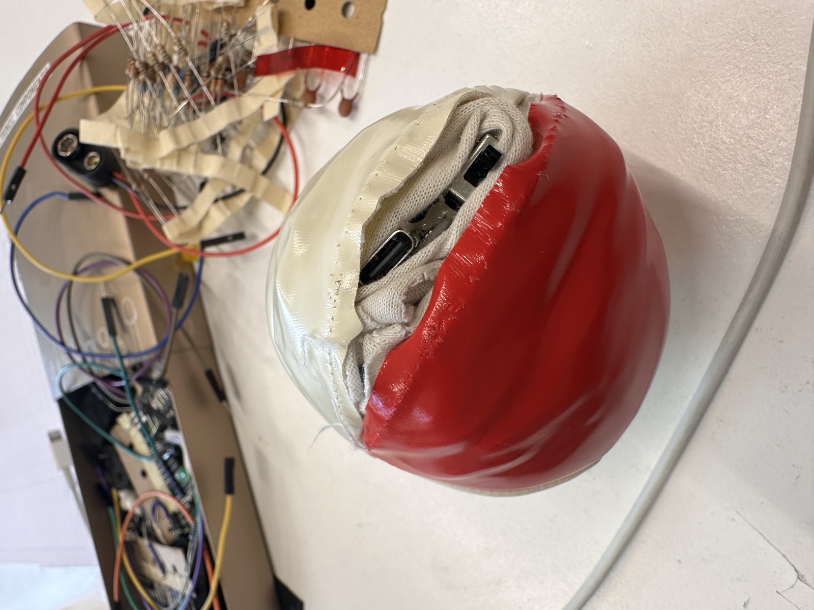 The finished juggling ball with the sewn-in electronics visible through the opening, prototyping circuit in the background