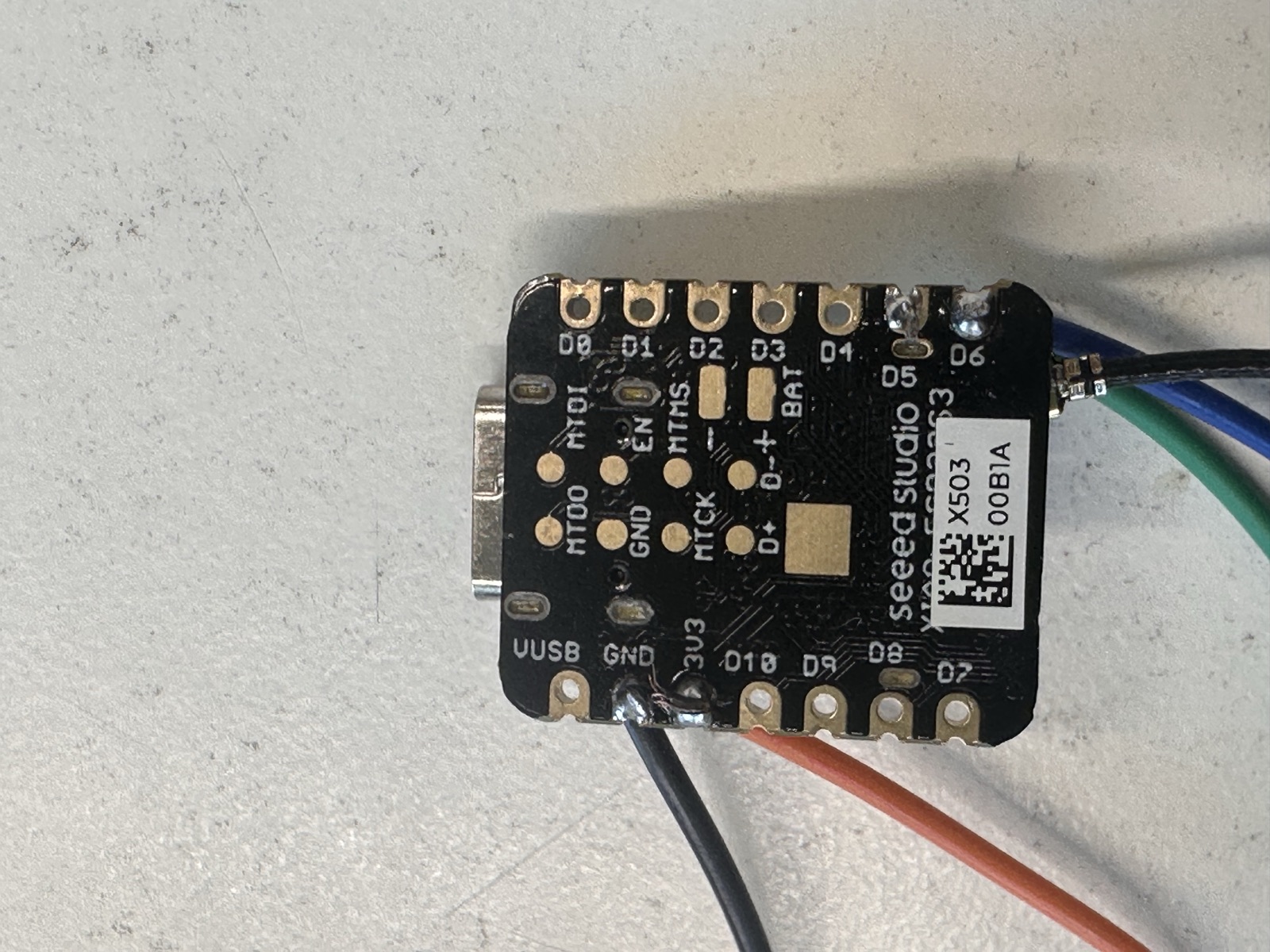 Close-up of the Seeed Studio XIAO ESP32-S3 microcontroller with soldered wires